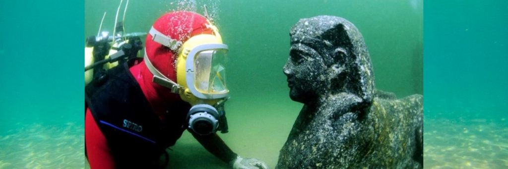 подводный археолог и каменная статуя на дне моря