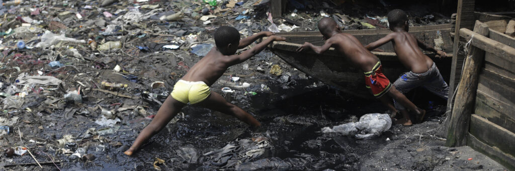 дети в грязи тянут лодку в Лагосе, Нигерия