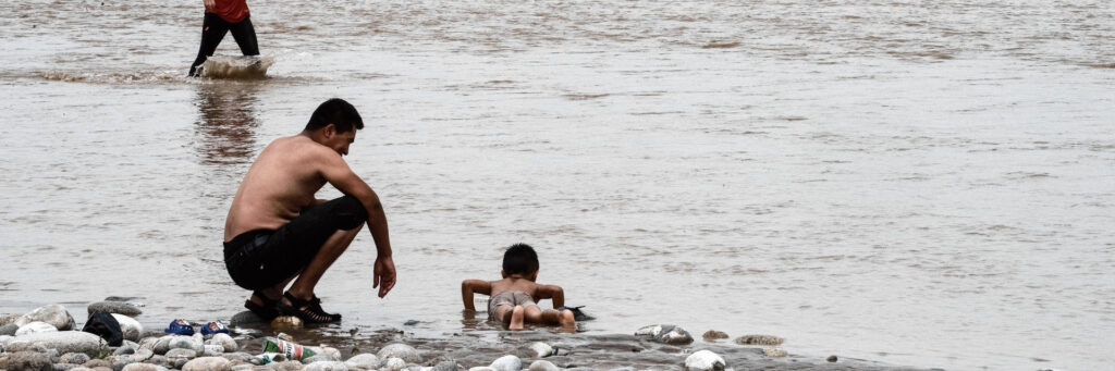 Река в городе Хотан. мужчина и ребенок купаются